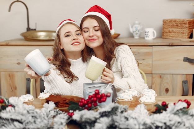 Free photo women have a cupcakes. friends in a christmass decorations. girl in a santa's hat.