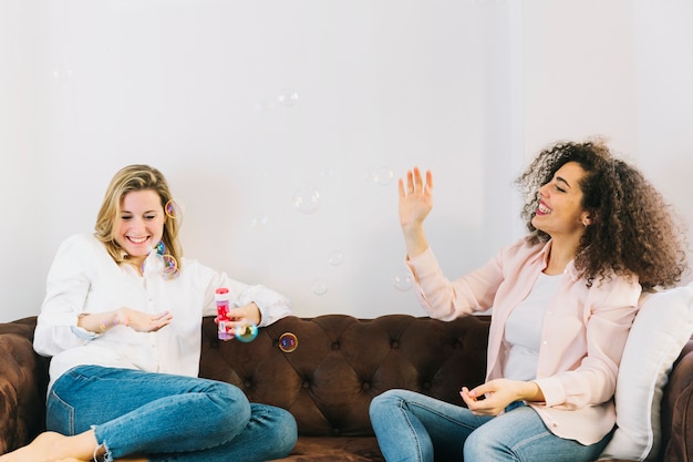 Women having fun with bubbles on sofa