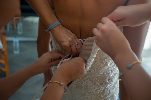 "Women helping bride to get dressed"