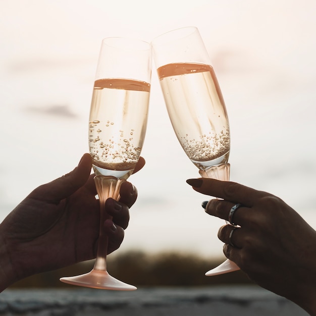 Donne in possesso di bicchieri di champagne sullo sfondo del tramonto