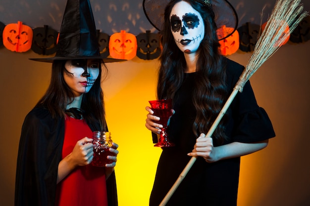 Free photo women holding drinks dressed as witches