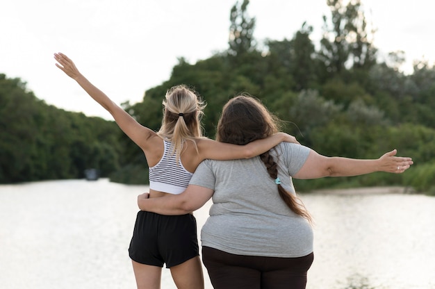 Free photo women holding each other back view