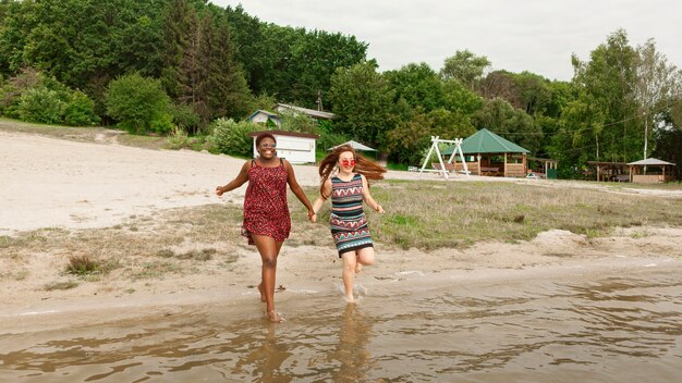 Women holding hands and getting into the water at the beach