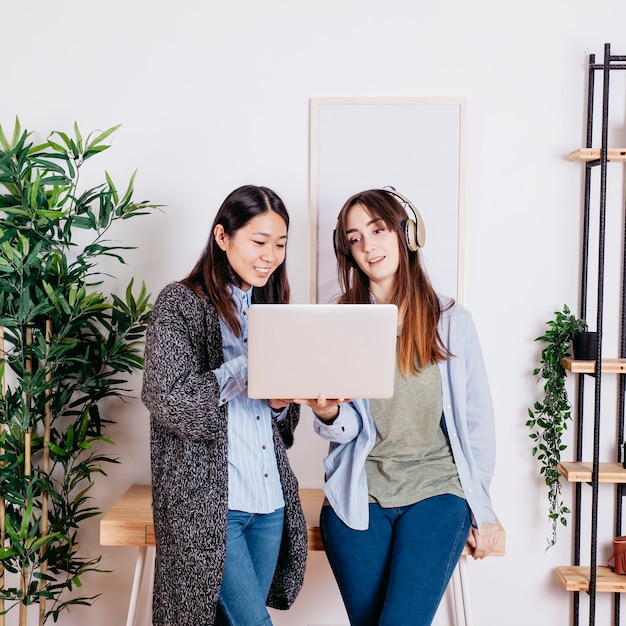 Women holding laptop and using headphones