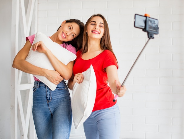 Donne in possesso di cuscino e prendendo selfie