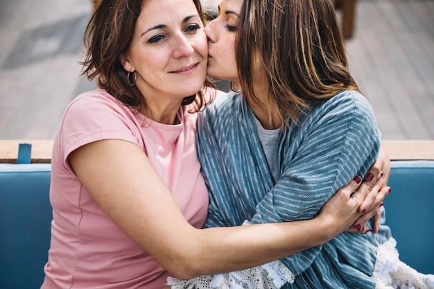 Women hugging and kissing on sofa