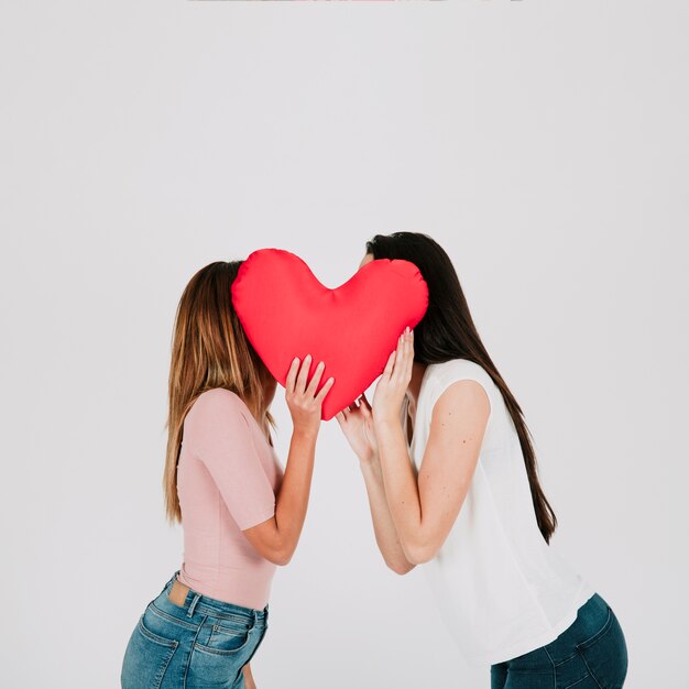 Women kissing behind heart