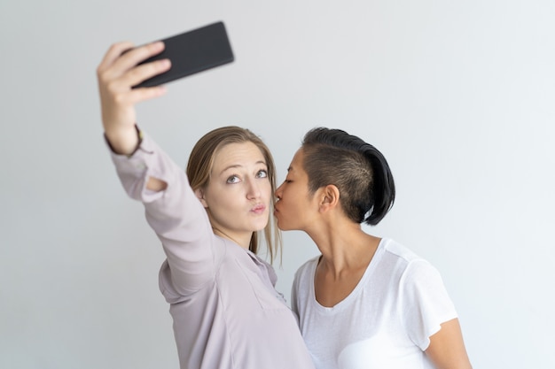 Women kissing and taking selfie photo