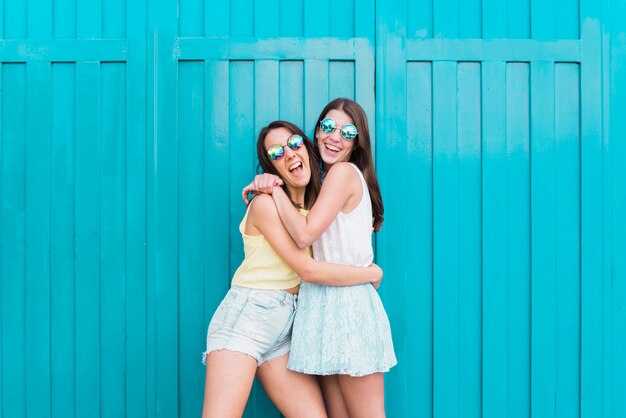 Women laughing and hugging while standing on street