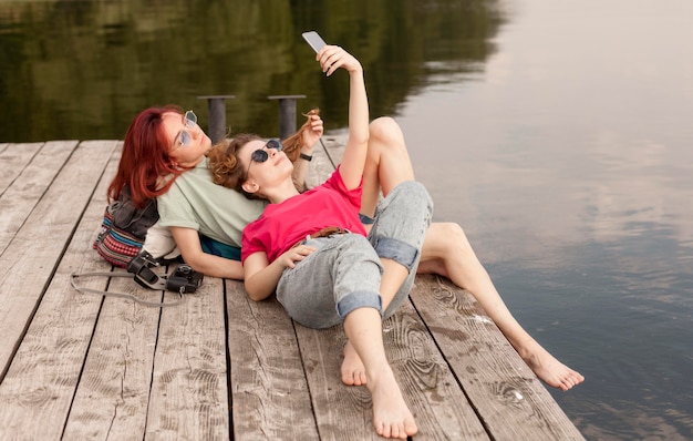 Women laying on dock and taking selfie