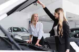 Free photo women looking at each other with car hood open