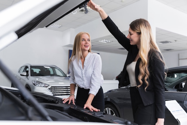 車のボンネットを開けてお互いを見ている女性