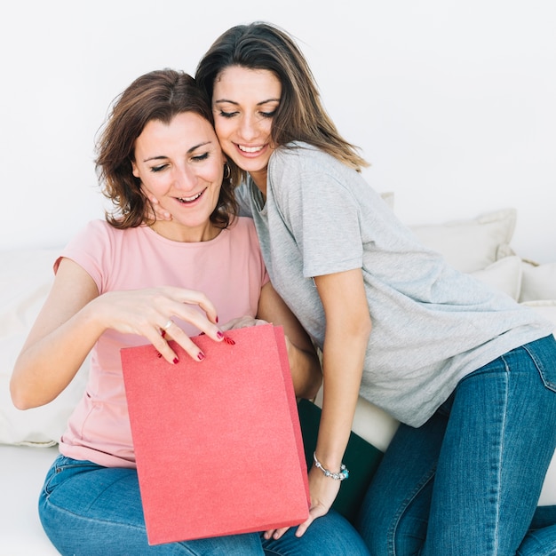 Free photo women looking at present in red paper bag