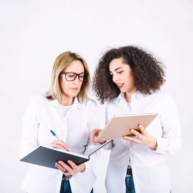 Women making notes from tablet