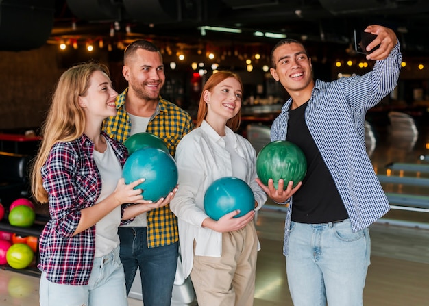 Women and men holding colorful bowling balls