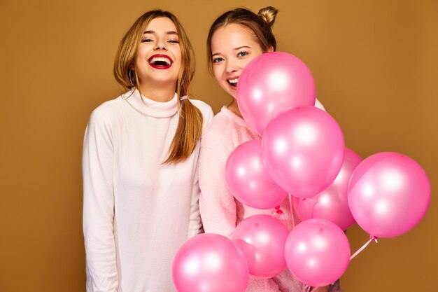 Women models with pink air balloons on golden wall