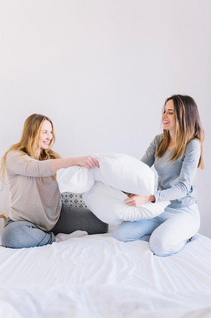 Women in pajamas fighting with pillows