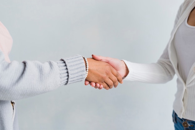 Women in pale clothes shaking hands in greeting