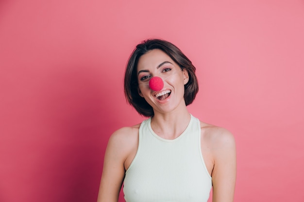 Donne su sfondo rosa piuttosto divertente e sorridente giovane donna che indossa il naso da clown, atmosfera di festa