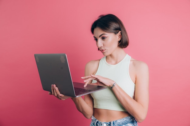 Donne su sfondo rosa piuttosto sorridente tenendo il pc portatile