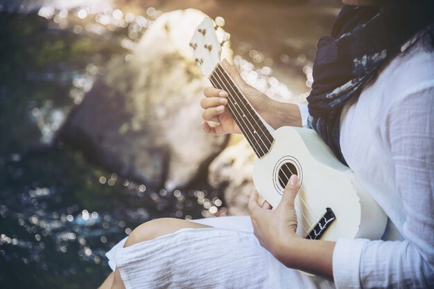 Women play ukulele new to the waterfall 