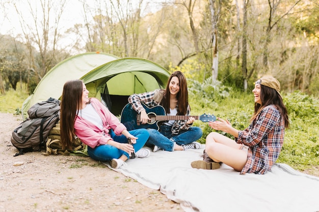 Foto gratuita donne che suonano la chitarra vicino alla tenda