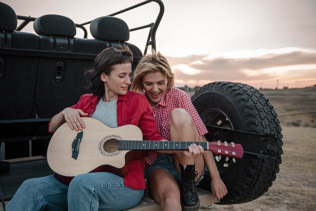 Women playing guitar while traveling by car