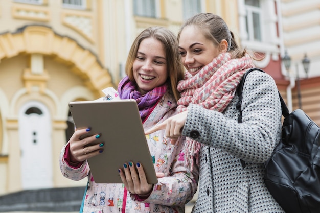 Women pointing at tablet on street