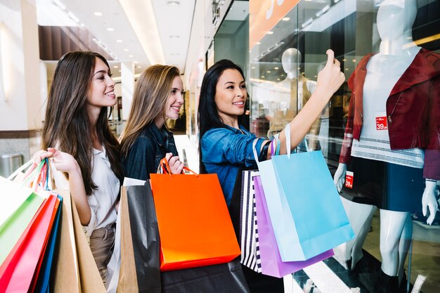 Women posing for selfie with paper bags
