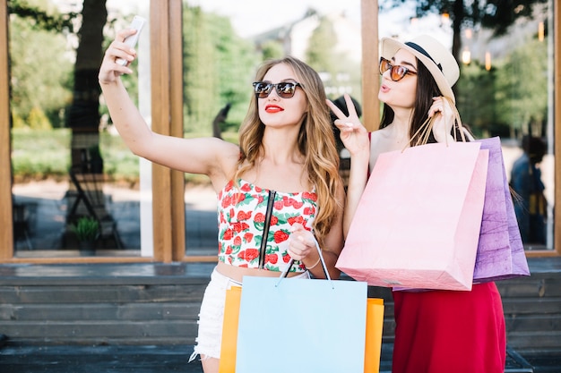 Women posing for selfie with paper bags