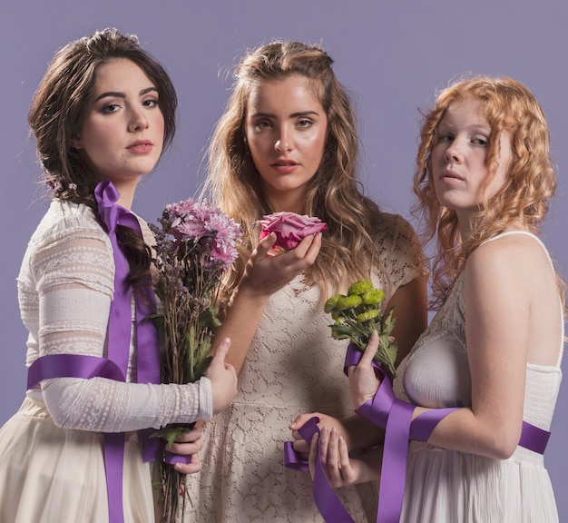 Free photo women posing with flowers and ribbon