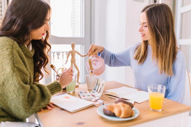 Women pouring tea while drawing