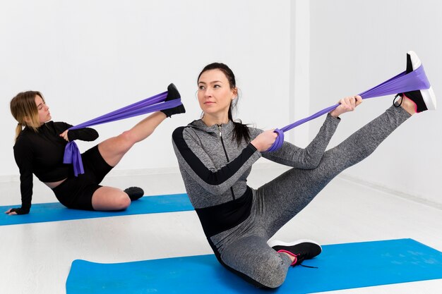 Женщины тренируются на коврике в тренажерном зале