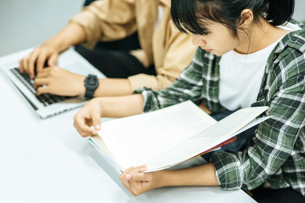 Le donne leggono libri e gli uomini usano i laptop per cercare libri nelle biblioteche.