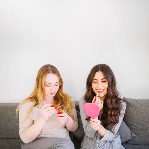 Women rouging lips and polishing nails