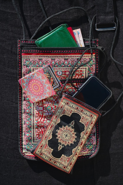 Free photo women's bag in traditional turkish style next to the phone purse and purse on black cloth top view the idea of combining traditional and modern culture