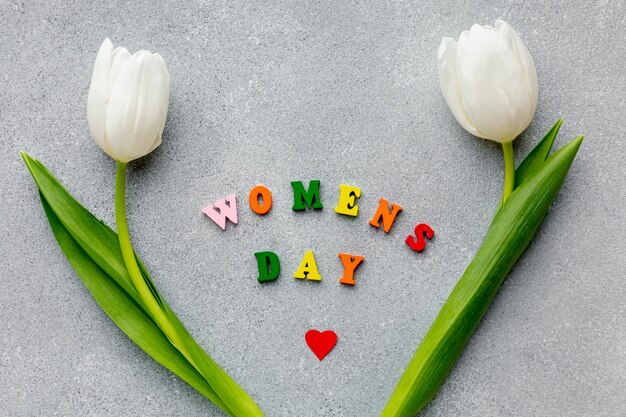 Women's day lettering on cement with white tulips