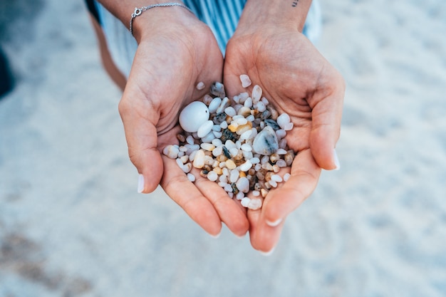 Women's hands are holding a lot of small pebbles