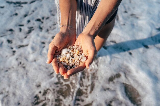 Women's hands are holding a lot of small pebbles