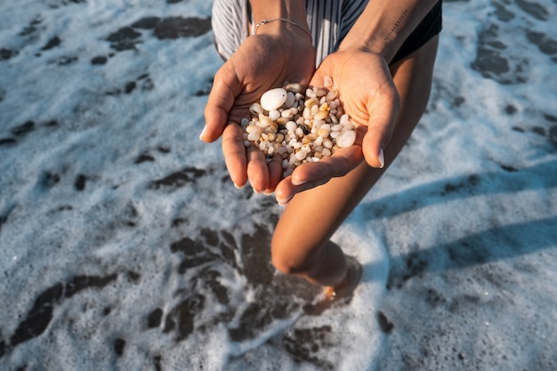 Women's hands are holding a lot of small pebbles