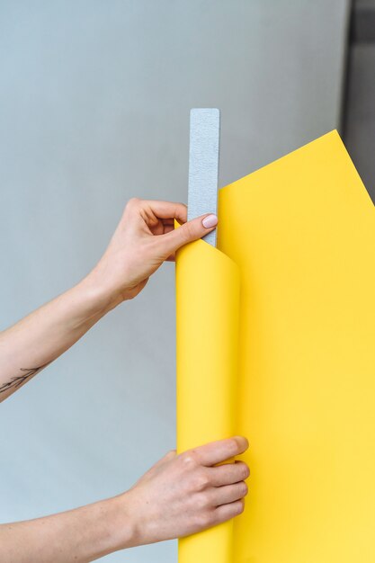 Women's hands wrap a gray nail file in paper