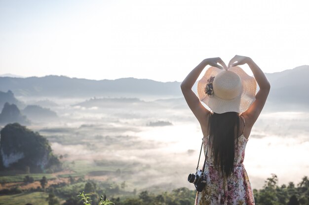 Women show heart-shaped gestures at the viewpoint on the mountain.