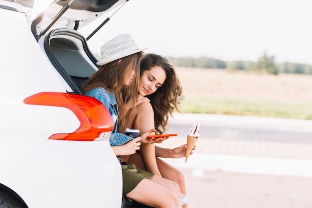 フィールドの背景に車のトランクに座っている女性