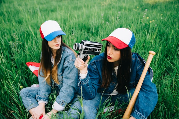 Women sitting in field in casual clothes and colored caps