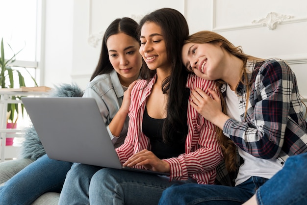 Women sitting on sofa and spending time together with laptop 