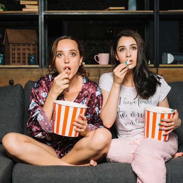 Women sitting on sofa staring while watching television