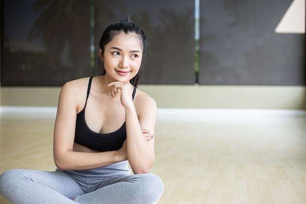 Women sitting wearing exercise clothes and chin on their hands are smiling.