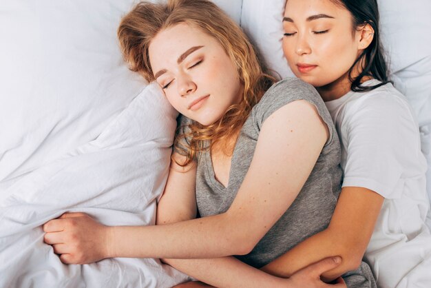 Women sleeping together hugging in bed