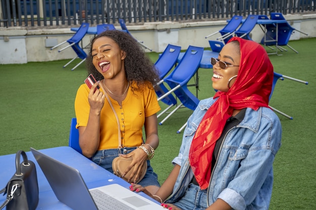 Women smiling and shopping online while sitting in a cafe