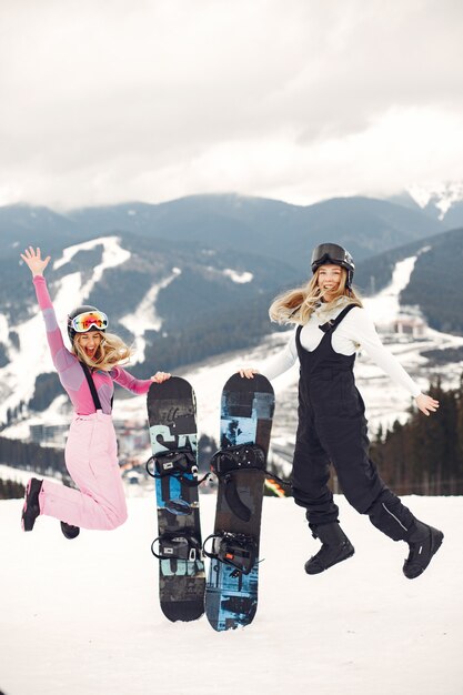 Женщины в костюме сноуборда. Спортсменки на горе со сноубордом в руках на горизонте. Концепция спорта